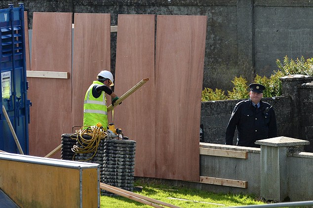 Gardai watch over wortkmen as they board up around the Tuam Mother and Baby graveyard site as a preliminary excavation is to take place next week. The tests were requested by the Commission of Investigation into Mother and Baby Homes, which was established following allegations about the deaths of 800 babies and the manner in which they were buried in Tuam. The commission said the test excavation will take around five weeks to complete. It said a sample of ground will be excavated by a team of specialist archaeologists.. Photo: Ray Ryan